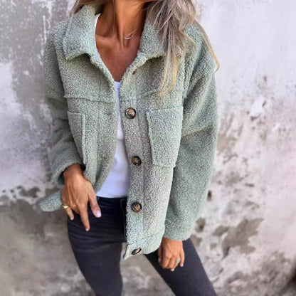 Giacca in pile verde salvia con bottoni, indossata da una donna su sfondo grigio. Moda autunnale, abbigliamento casual, stile confortevole.