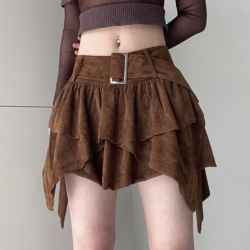 Gonna asimmetrica marrone in pelle scamosciata con cintura, indossata da una persona con top a maniche lunghe marrone. Moda autunnale elegante.