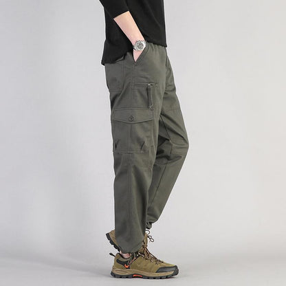 Pantaloni cargo uomo verde militare, tasche multiple, stile casual, abbinati a scarpe trekking marroni. Moda outdoor, abbigliamento versatile.