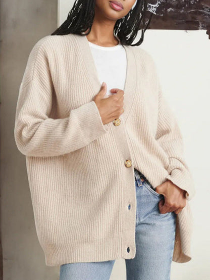 Donna con cardigan beige oversize in maglia, abbinato a jeans e maglietta bianca. Moda autunnale casual, stile confortevole ed elegante.