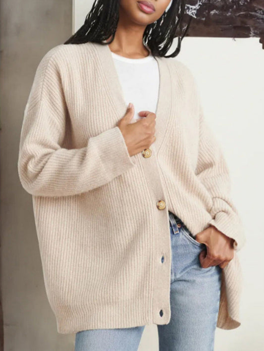 Donna con cardigan beige oversize in maglia, abbinato a jeans e maglietta bianca. Moda autunnale casual, stile confortevole ed elegante.