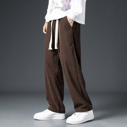 Pantaloni larghi marroni in velluto a coste, indossati con felpa bianca e sneakers bianche, moda casual uomo, stile autunnale.