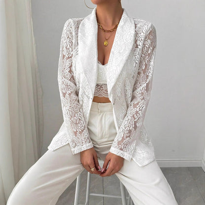 Donna con giacca di pizzo bianco, top e pantaloni coordinati, seduta su sgabello. Moda elegante, abbigliamento femminile, stile sofisticato.