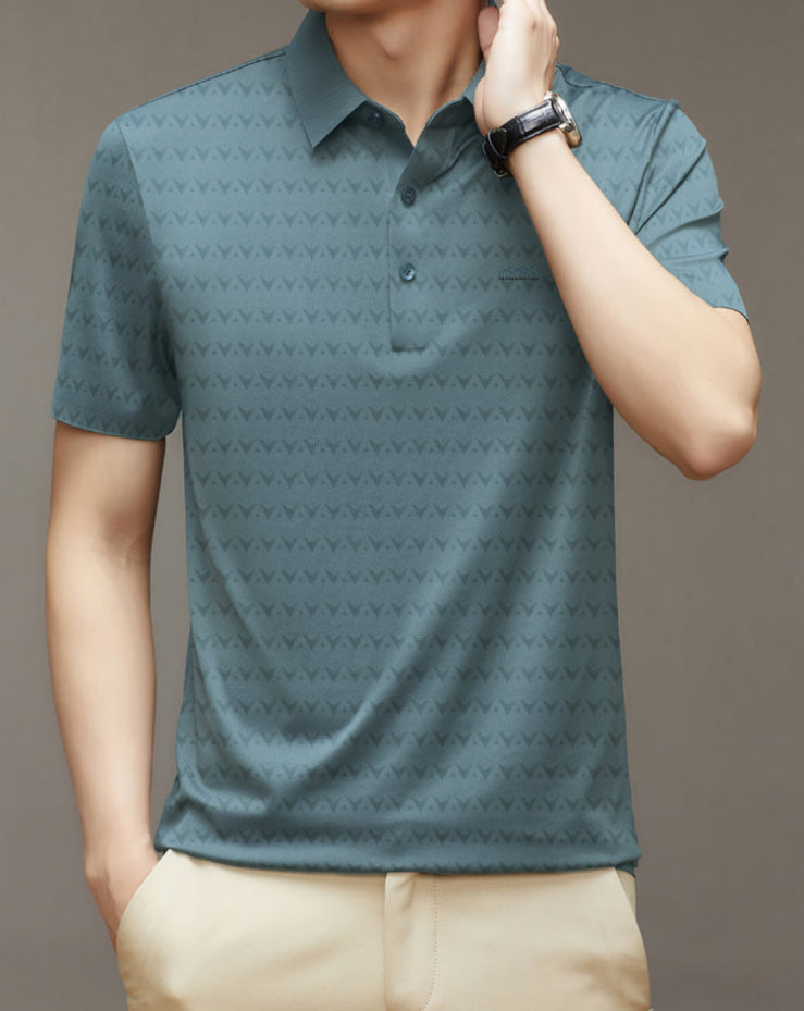 Uomo con polo verde a maniche corte con motivo geometrico, orologio nero al polso, pantaloni beige. Moda maschile casual elegante.