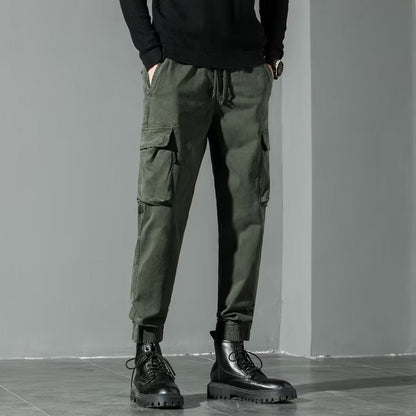 Pantaloni cargo verde militare da uomo, tasche multiple, abbinati a stivali neri robusti. Stile casual e funzionale per moda urbana.