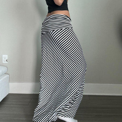 Pantaloni a righe bianche e nere, larghi e fluidi, indossati da una persona in piedi su pavimento in legno. Stile casual, moda donna.
