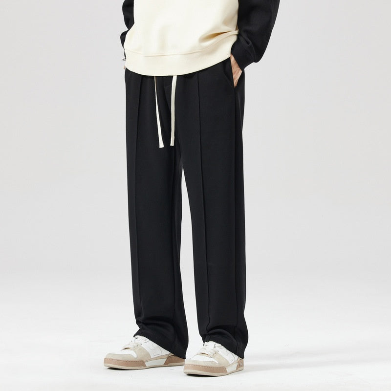 Pantaloni neri eleganti da uomo con coulisse, abbinati a sneakers bianche e felpa chiara. Moda casual, abbigliamento maschile moderno.