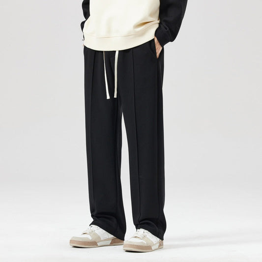 Pantaloni neri eleganti da uomo con coulisse, abbinati a sneakers bianche e felpa chiara. Moda casual, abbigliamento maschile moderno.