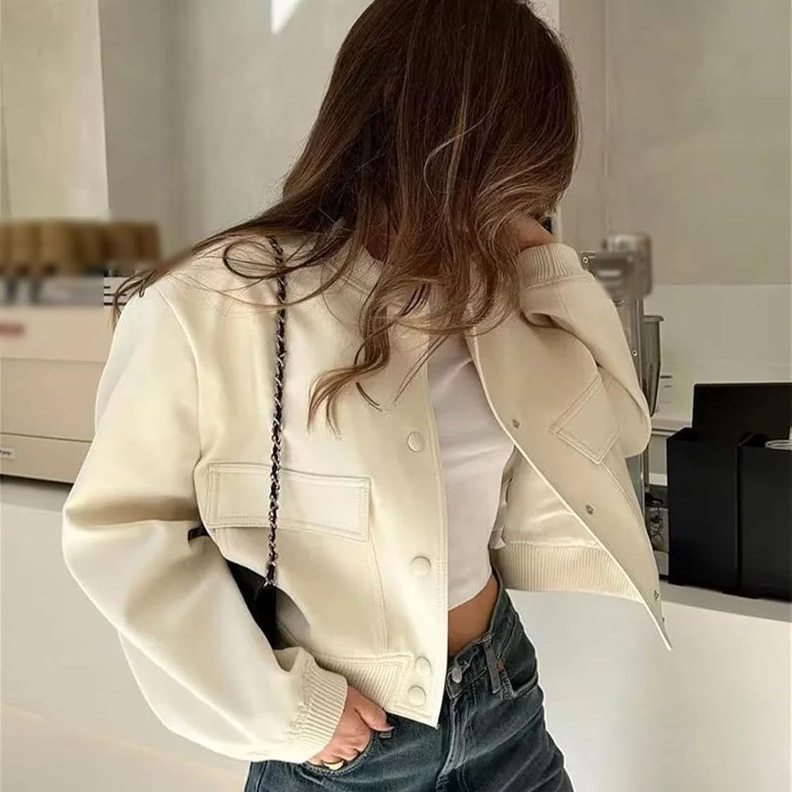 Giacca corta bianca da donna, abbinata a top bianco e jeans. Moda casual femminile, stile urbano, tendenze abbigliamento autunnale.