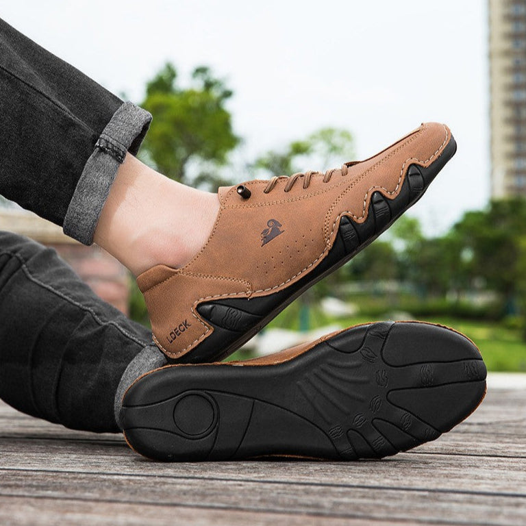 Scarpe da uomo casual in pelle marrone, suola nera antiscivolo, indossate all'aperto su pavimento in legno. Design moderno e confortevole.