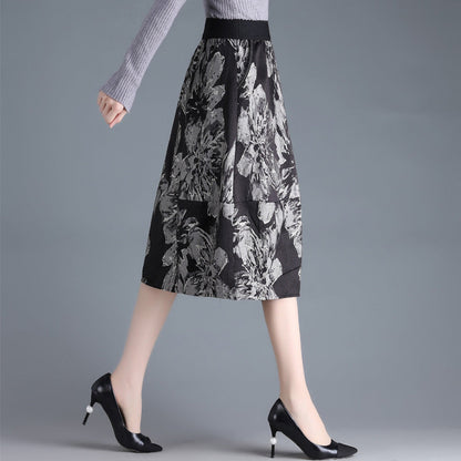 Gonna midi nera a fiori grigi, indossata con maglione grigio e tacchi neri. Moda donna elegante, abbigliamento autunnale chic.