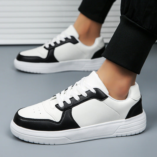Scarpe da ginnastica bianche e nere su pavimento grigio, indossate da una persona. Design moderno, suola spessa, perfette per moda casual.