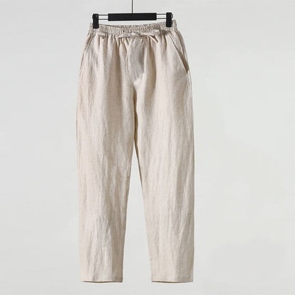 Pantaloni in lino beige appesi su gruccia, design casual, elastico in vita, tasche laterali. Abbigliamento estivo leggero e traspirante.