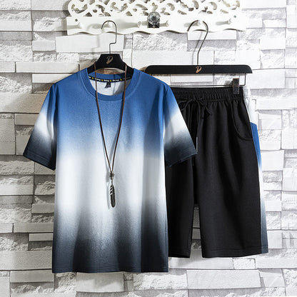 Completo estivo uomo: maglietta sfumata blu-bianco e pantaloncini neri, appesi su grucce. Moda casual, abbigliamento estivo, outfit maschile.