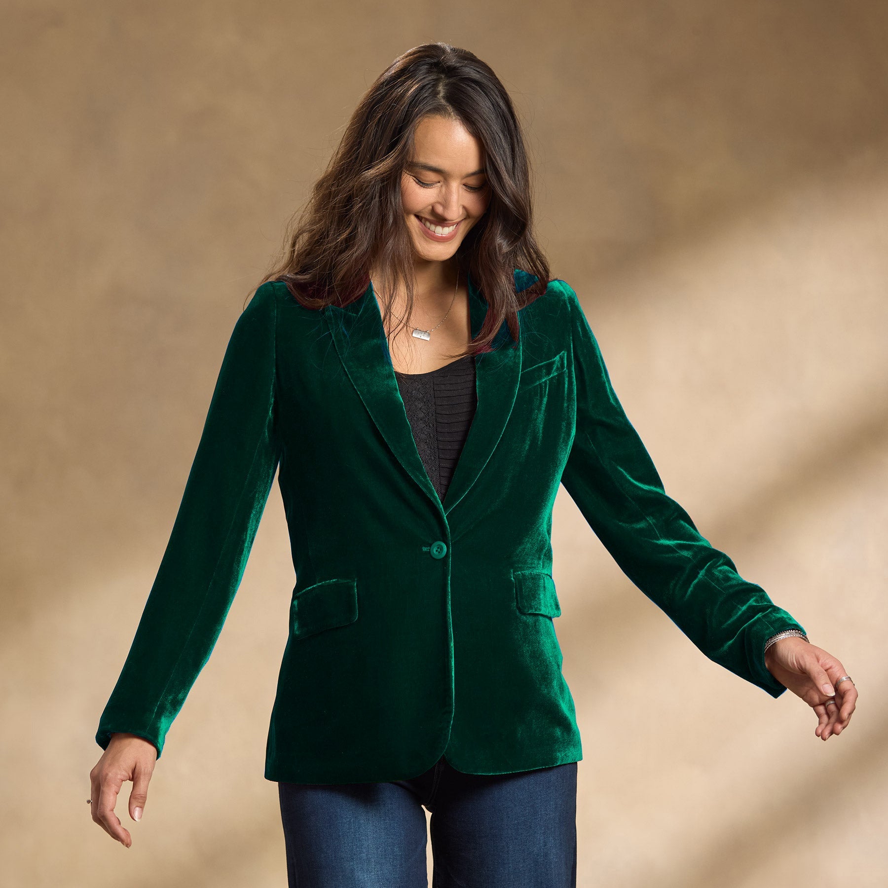 Donna sorridente con giacca di velluto verde, camicia nera e jeans. Moda autunnale elegante, abbigliamento casual chic, tendenze moda 2023.