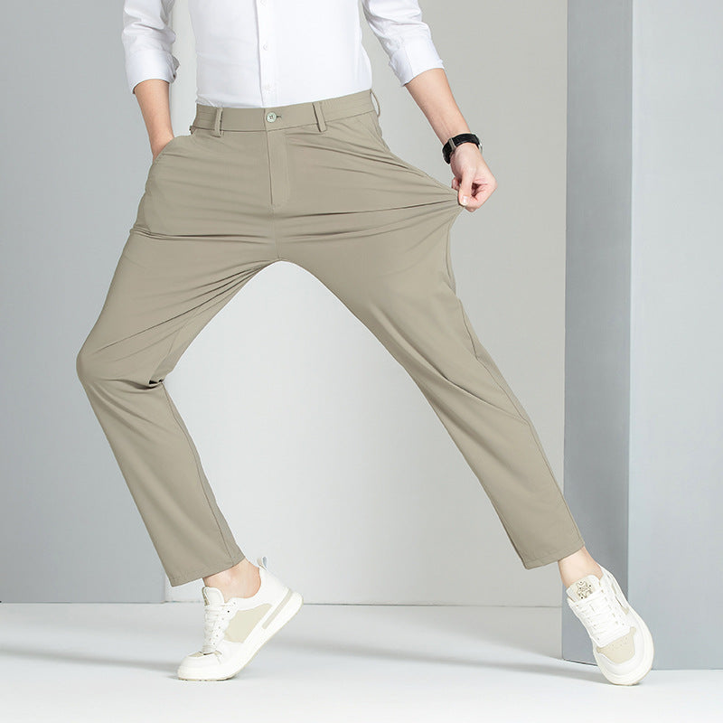 Pantaloni beige elasticizzati da uomo, indossati con camicia bianca e sneakers bianche, evidenziano comfort e stile casual.
