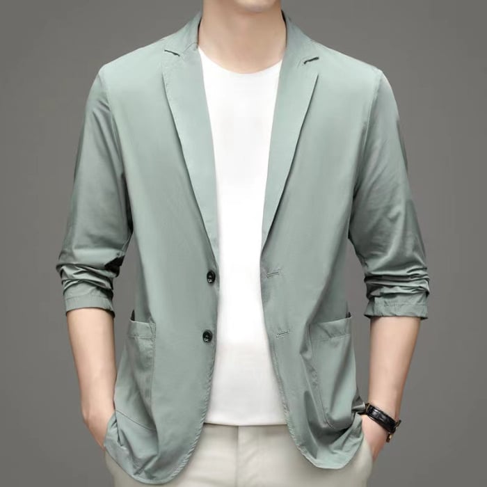 Giacca casual verde chiaro da uomo, maniche arrotolate, abbinata a t-shirt bianca e pantaloni chiari. Stile moderno ed elegante.