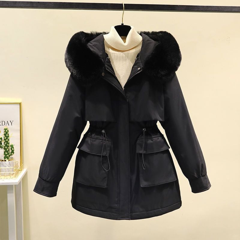 Giacca invernale nera con cappuccio in pelliccia sintetica, chiusura a zip, tasche frontali e cintura regolabile, appesa su sfondo neutro.