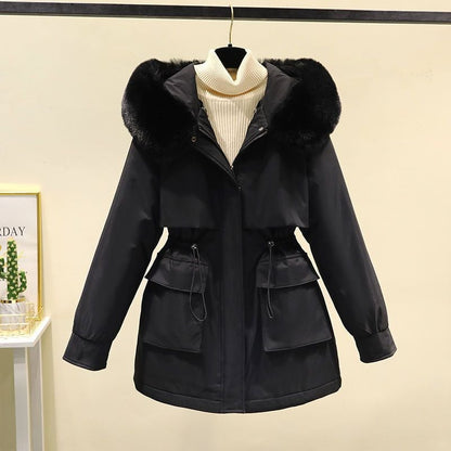 Giacca invernale nera con cappuccio in pelliccia sintetica, chiusura a zip, tasche frontali e cintura regolabile, appesa su sfondo neutro.