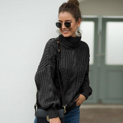 Donna con occhiali da sole indossa maglione nero a collo alto, orecchini grandi e borsa a tracolla. Moda autunnale, stile casual chic.