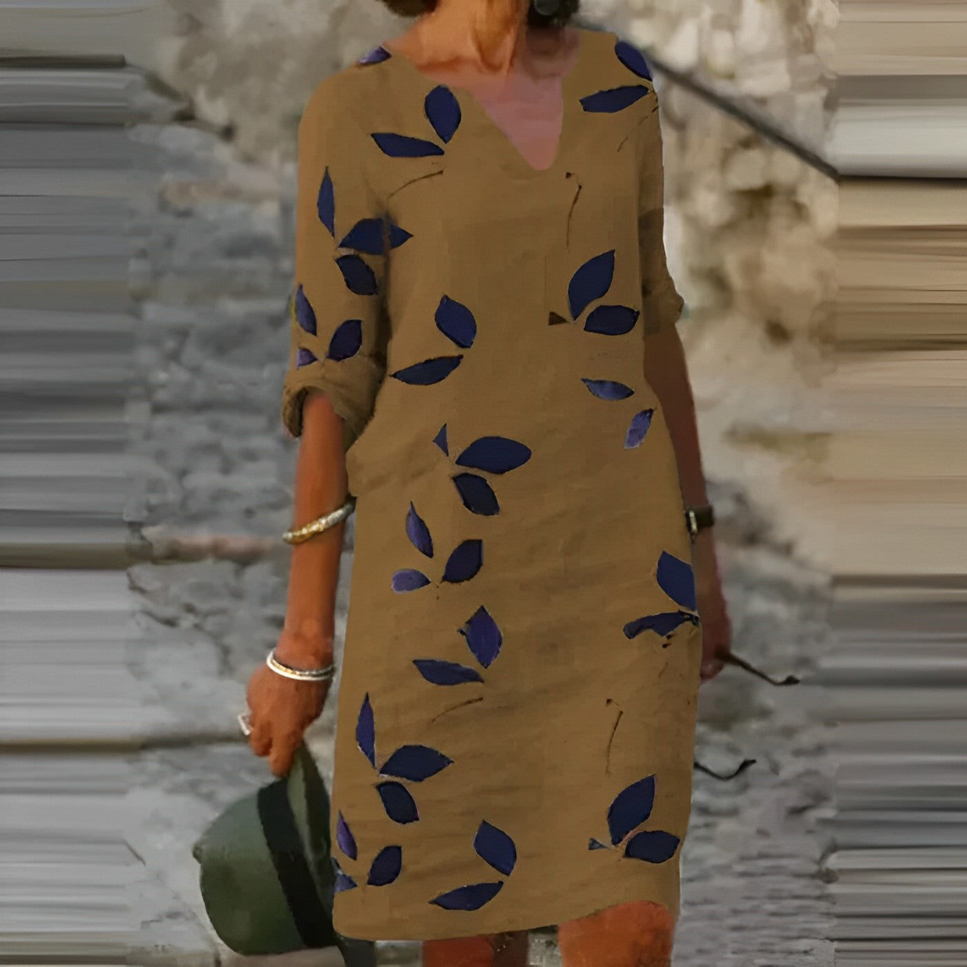Abito marrone con motivo a foglie blu, maniche arrotolate, indossato da una donna all'aperto. Stile casual, moda femminile, abbigliamento estivo.