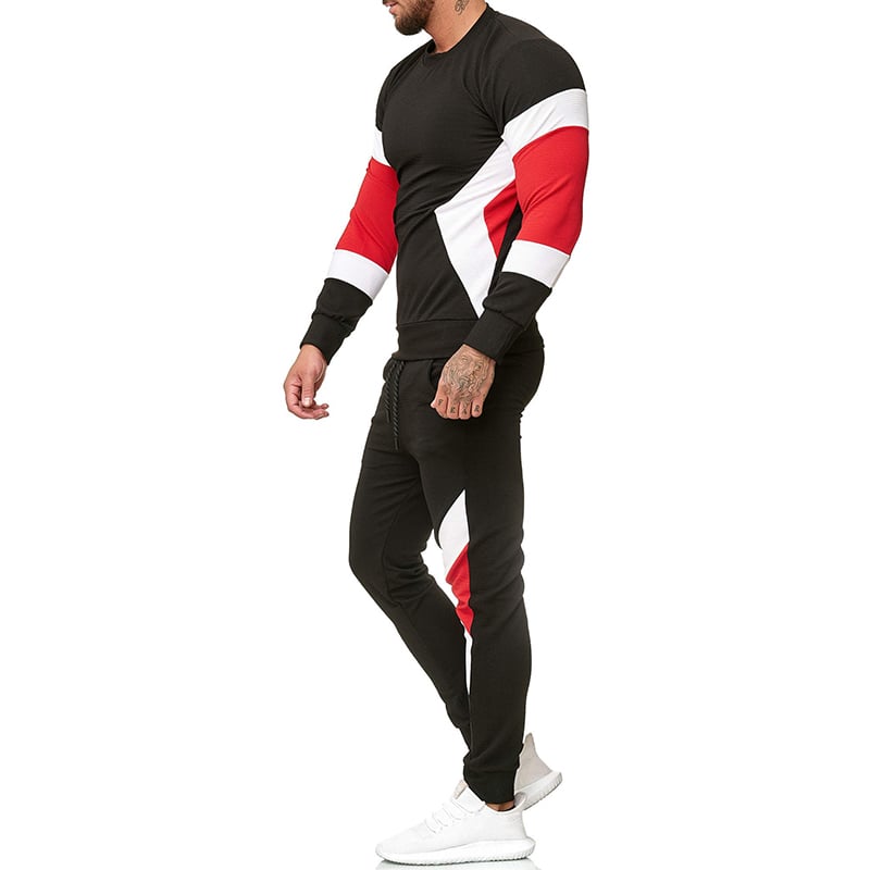 Uomo in tuta sportiva nera con dettagli rossi e bianchi, scarpe da ginnastica bianche. Abbigliamento casual, moda uomo, stile sportivo.