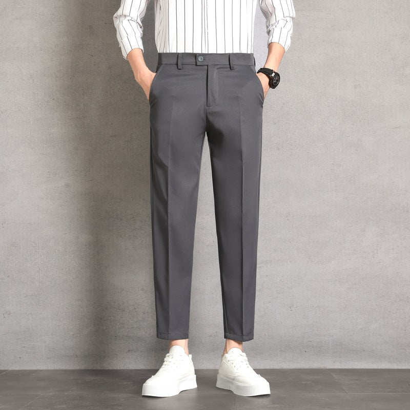 Pantaloni eleganti grigi da uomo, abbinati a camicia a righe bianche e scarpe da ginnastica bianche, moda casual moderna.