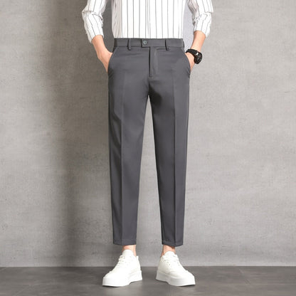 Pantaloni eleganti grigi da uomo, abbinati a camicia a righe bianche e scarpe da ginnastica bianche, moda casual moderna.