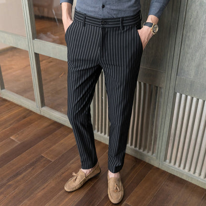 Pantaloni eleganti a righe verticali nere e bianche, indossati con mocassini marroni su pavimento in legno. Moda uomo, abbigliamento formale.