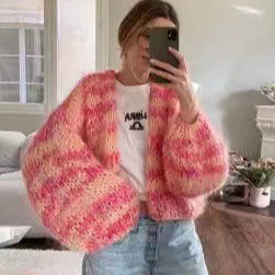 Donna con cardigan rosa e arancione a maglia grossa, selfie allo specchio, indossa jeans e t-shirt bianca. Stile casual, moda autunnale.