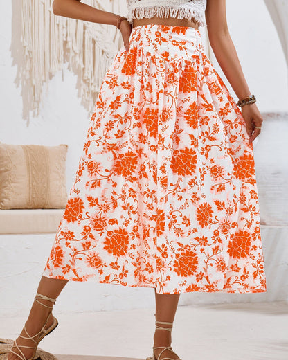 Gonna lunga a fiori arancioni su sfondo bianco, indossata da una donna. Stile boho chic, perfetta per l'estate. Tessuto leggero e decorazioni floreali.