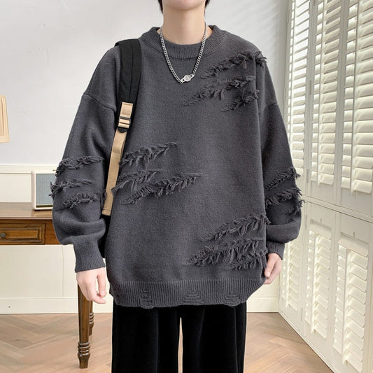 Maglione oversize grigio scuro con dettagli strappati, indossato da una persona con zaino nero. Stile casual, moda autunnale, tendenza streetwear.