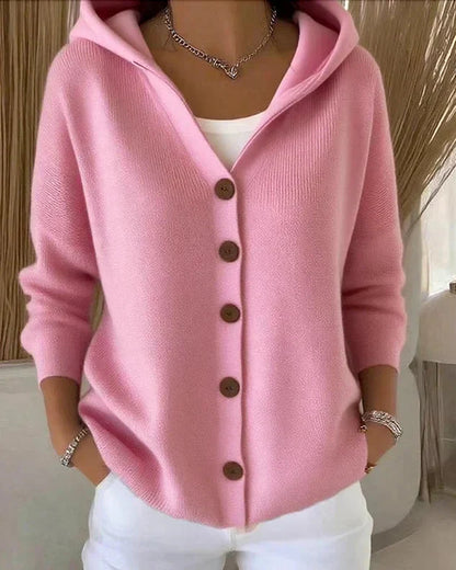 Donna con cardigan rosa in cashmere, bottoni marroni, indossa pantaloni bianchi. Moda autunnale, abbigliamento casual elegante, tendenze 2023.