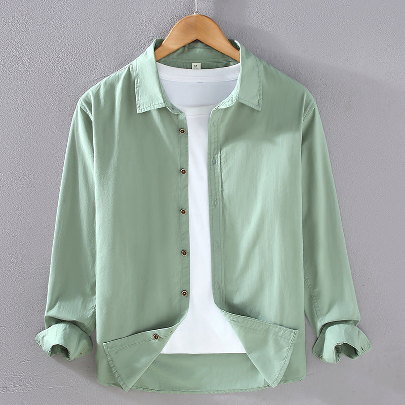 Camicia verde chiaro da uomo su gruccia, maniche lunghe arrotolate, abbinata a t-shirt bianca. Moda casual, abbigliamento maschile elegante.