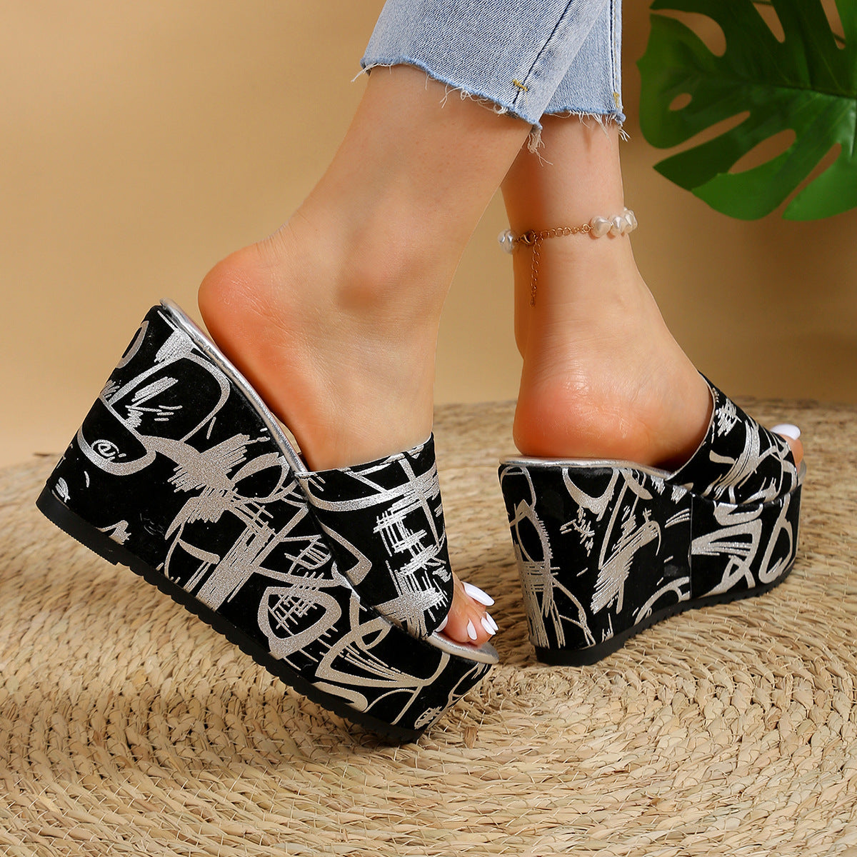 Sandali con zeppa neri con graffiti bianchi, indossati su tappeto intrecciato. Moda estiva, calzature trendy, jeans strappati.