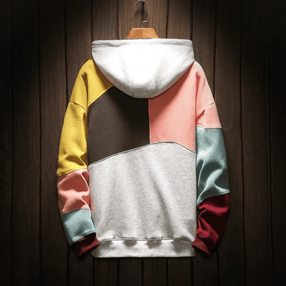 Felpa con cappuccio multicolore, design a blocchi, sfondo in legno. Moda casual, abbigliamento streetwear, tendenze autunno-inverno.