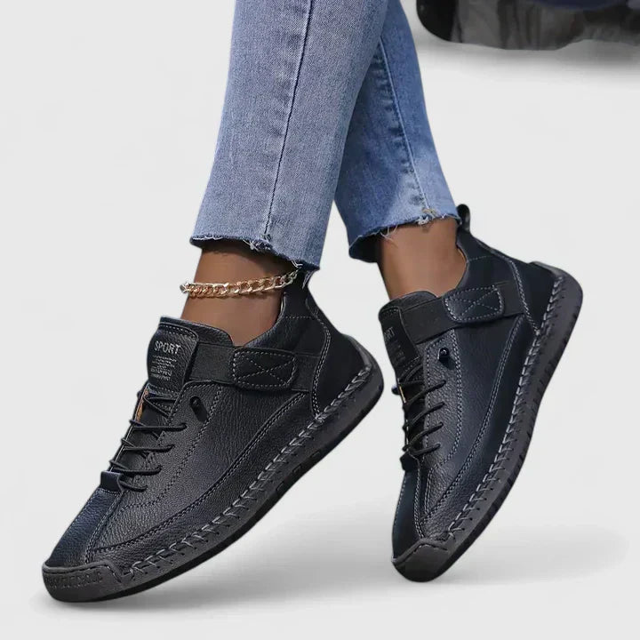 Jeans e scarpe sportive nere da donna con dettagli in pelle, suola robusta e cavigliera dorata. Moda casual, calzature eleganti, stile urbano.