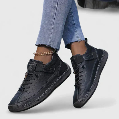 Jeans e scarpe sportive nere da donna con dettagli in pelle, suola robusta e cavigliera dorata. Moda casual, calzature eleganti, stile urbano.
