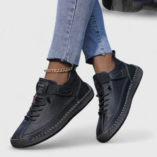 Jeans e scarpe sportive nere da donna con dettagli in pelle, suola robusta e cavigliera dorata. Moda casual, calzature eleganti, stile urbano.