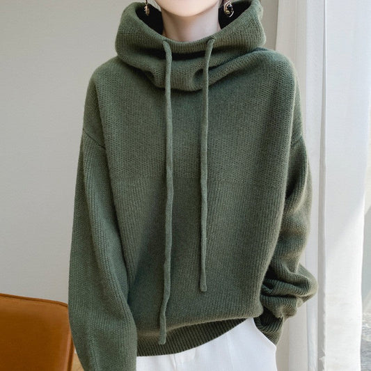 Maglione verde con cappuccio e lacci, tessuto morbido, indossato da una persona. Design casual, ideale per moda autunnale e invernale.