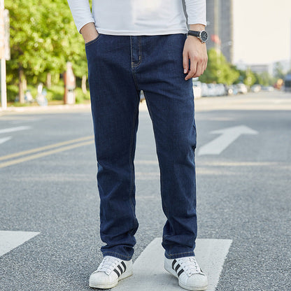 Uomo in jeans blu e maglietta bianca su strada cittadina, indossa scarpe sportive bianche. Moda casual maschile, abbigliamento urbano.