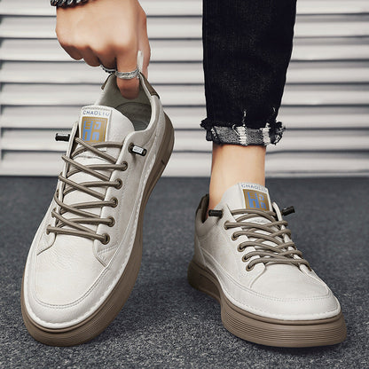 Scarpe da ginnastica uomo in pelle bianca, suola marrone, lacci grigi, indossate con jeans neri strappati. Design moderno e casual.