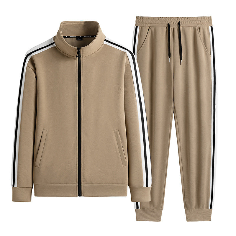 Tuta sportiva beige con giacca e pantaloni, dettagli a righe bianche e nere, zip frontale, tasche laterali, stile casual e moderno.