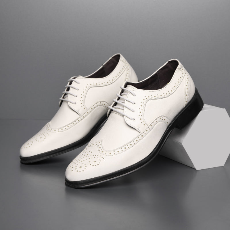 Scarpe eleganti da uomo bianche in pelle con dettagli brogue, suola nera, sfondo grigio. Scarpe formali di lusso, moda maschile.