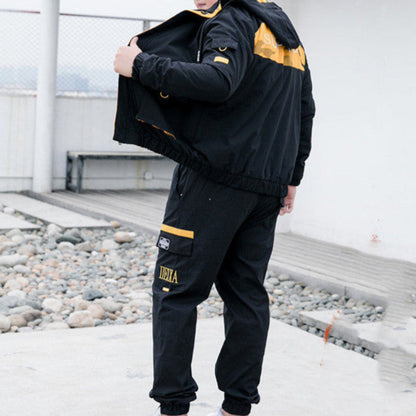 Giacca sportiva nera con dettagli gialli, indossata da uomo all'aperto. Abbigliamento casual, moda streetwear, stile urbano.