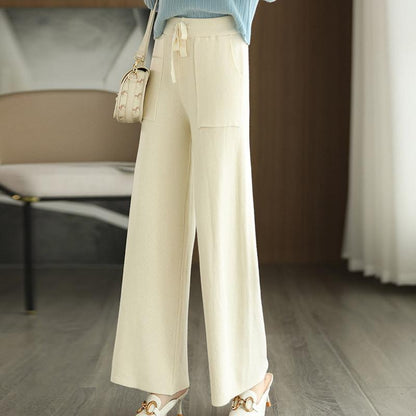 Pantaloni palazzo bianchi eleganti, tessuto leggero, abbinati a sandali con tacco e borsa a tracolla. Moda donna, abbigliamento estivo chic.