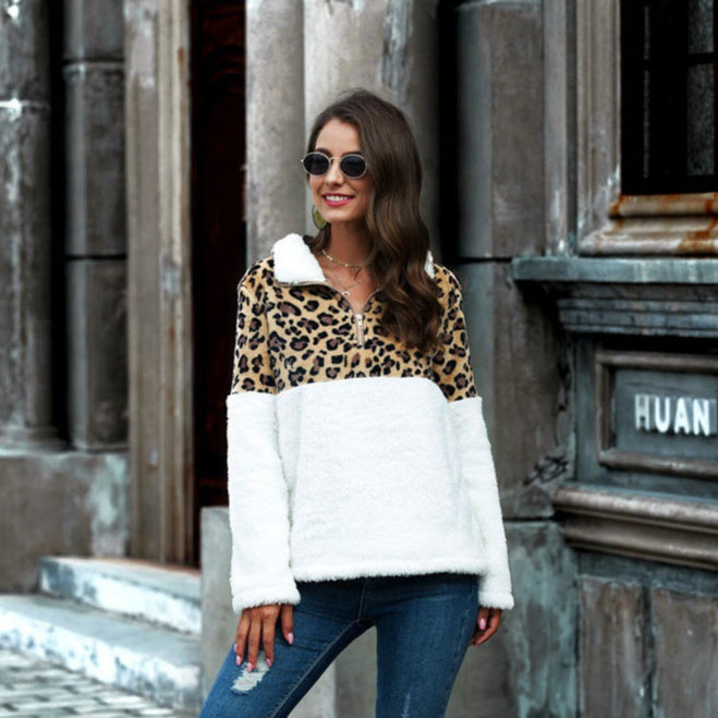 Donna con occhiali da sole indossa maglione leopardato e bianco, jeans aderenti. Moda autunnale, stile urbano, abbigliamento casual chic.