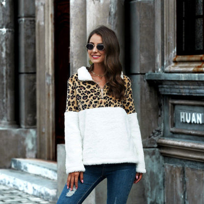 Donna con occhiali da sole indossa maglione leopardato e bianco, jeans aderenti. Moda autunnale, stile urbano, abbigliamento casual chic.