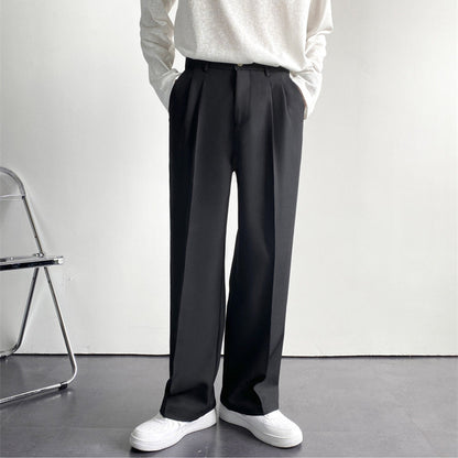 Pantaloni neri eleganti da uomo, taglio dritto, abbinati a maglia bianca e scarpe bianche, su sfondo minimalista. Moda maschile contemporanea.