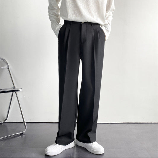 Pantaloni neri eleganti da uomo, taglio dritto, abbinati a maglia bianca e scarpe bianche, su sfondo minimalista. Moda maschile contemporanea.